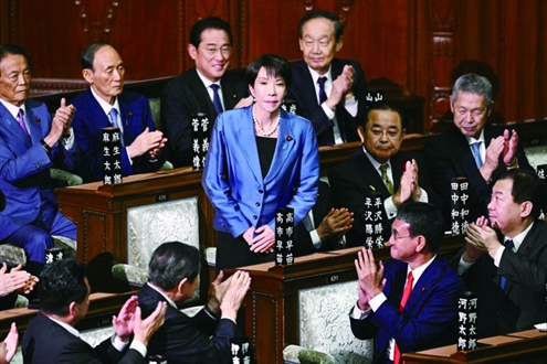 10月21日,在日本东京,自民党总裁高市早苗(中)在临时国会众议院首相指名选举中胜出后起身致谢。◎新华社发